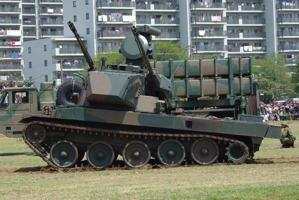 A Type 87 at The Goshisu Garrison displaying it's pneumatic suspension. The vehicle in the background is a Type 03 Medium-Range Surface-to-Air missile system